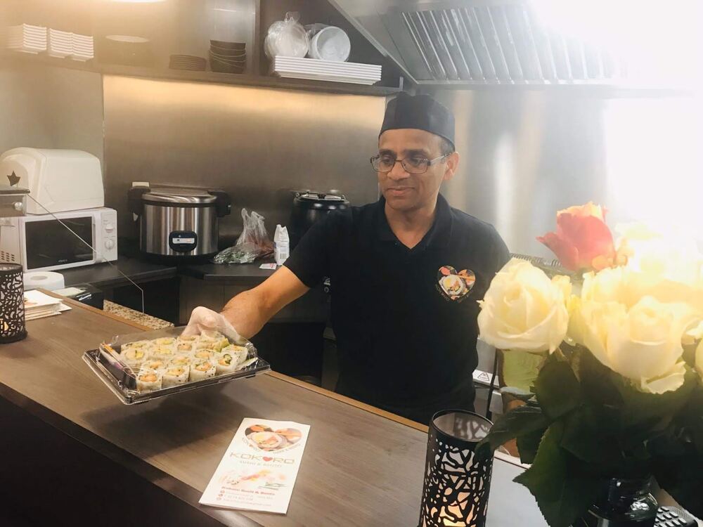 Chef at Kokoro Sushi & Bento presenting a fresh sushi platter at the counter